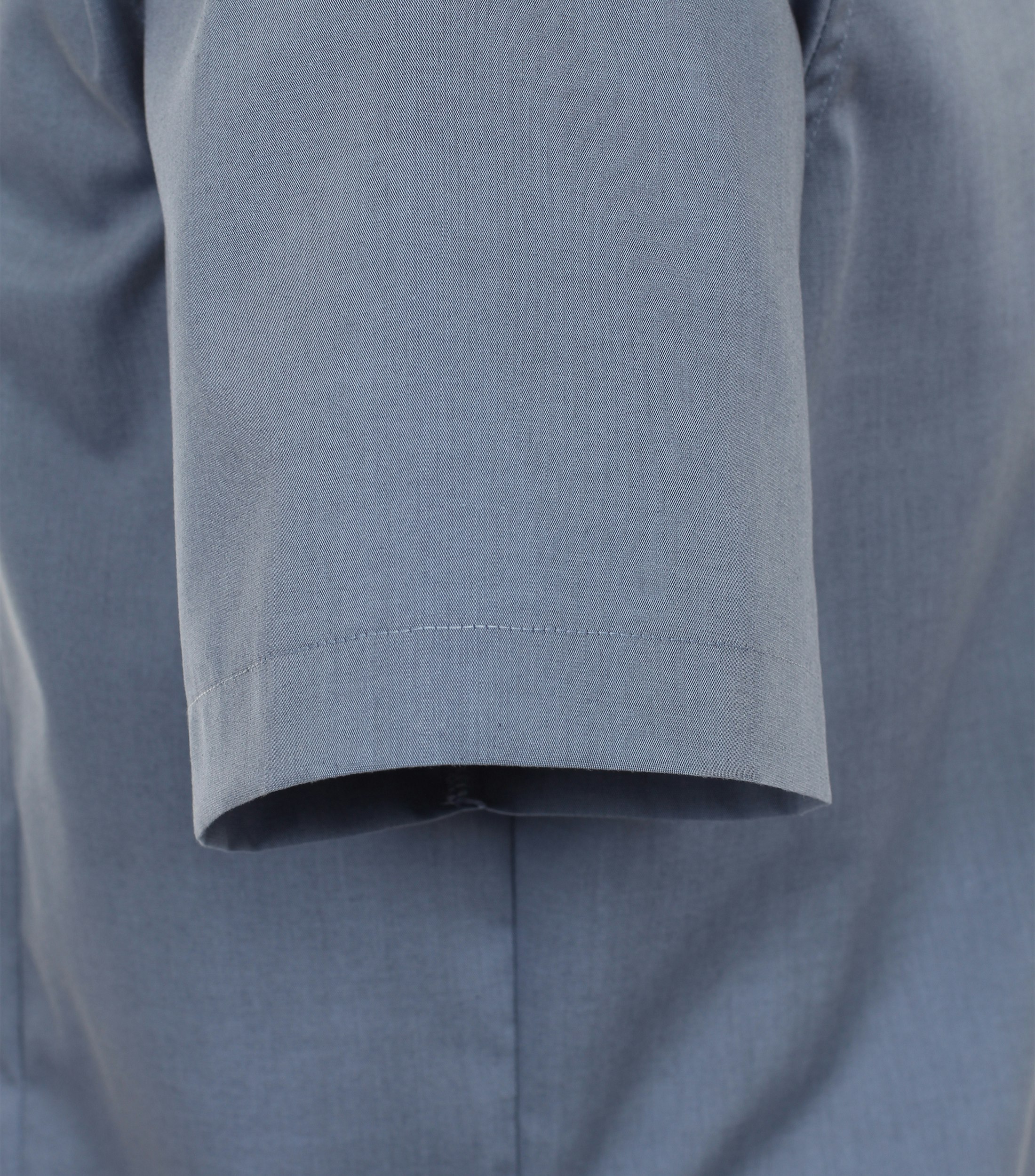 Das Model trägt ein Businesshemd im uni Muster in der Farbe sattes Mittelblau