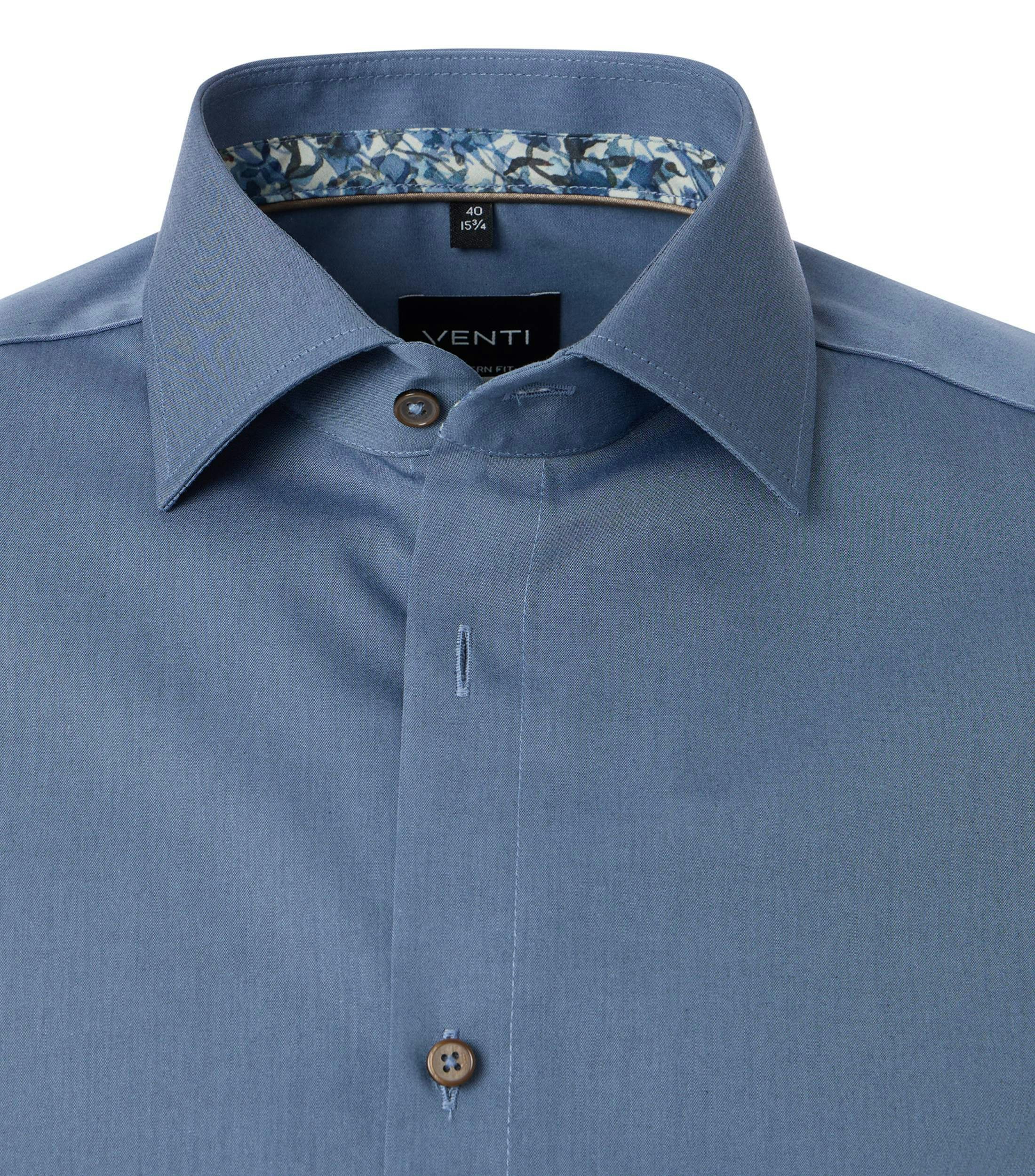 Das Model trägt ein Businesshemd im uni Muster in der Farbe Blau