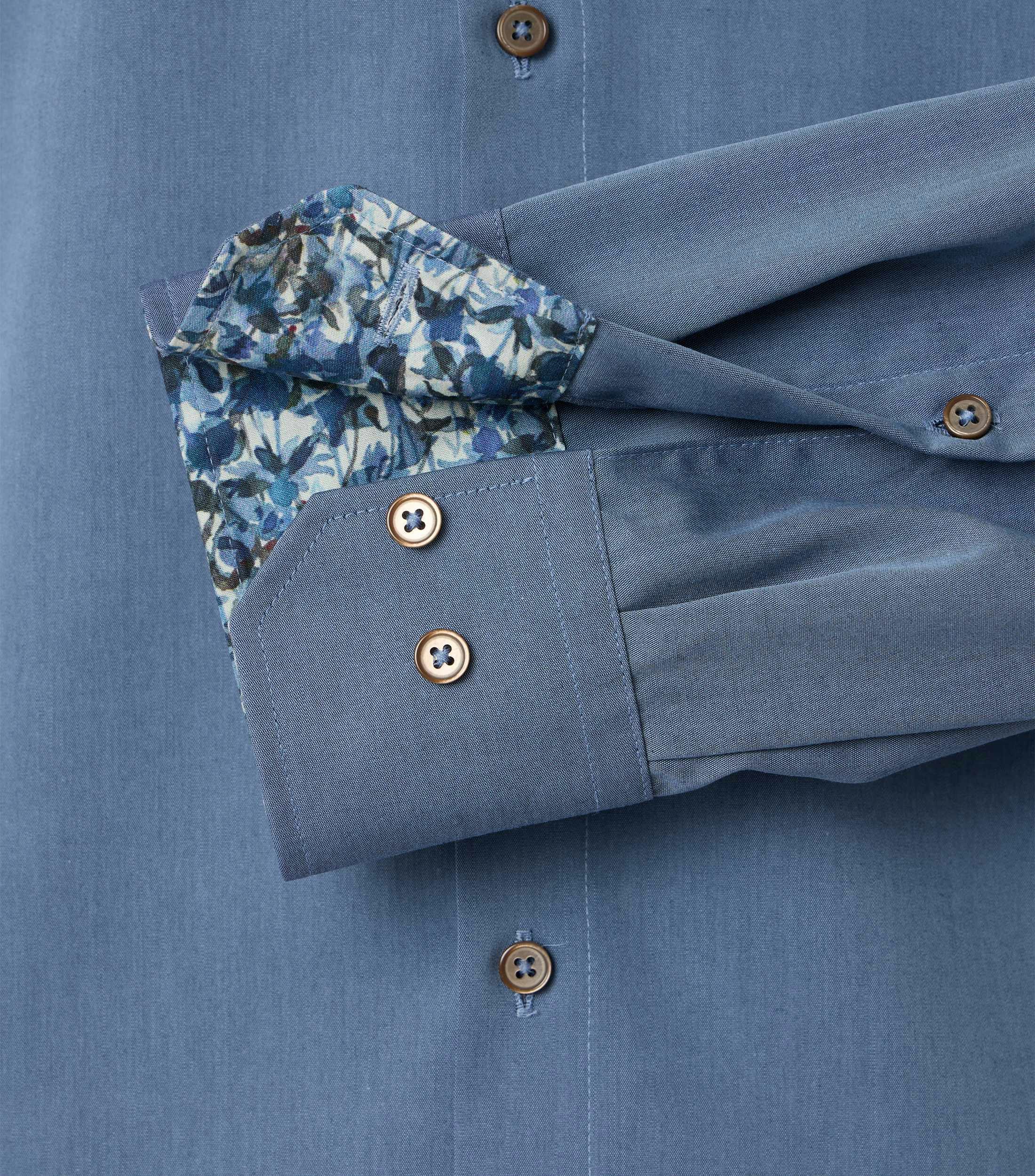 Das Model trägt ein Businesshemd im uni Muster in der Farbe Blau