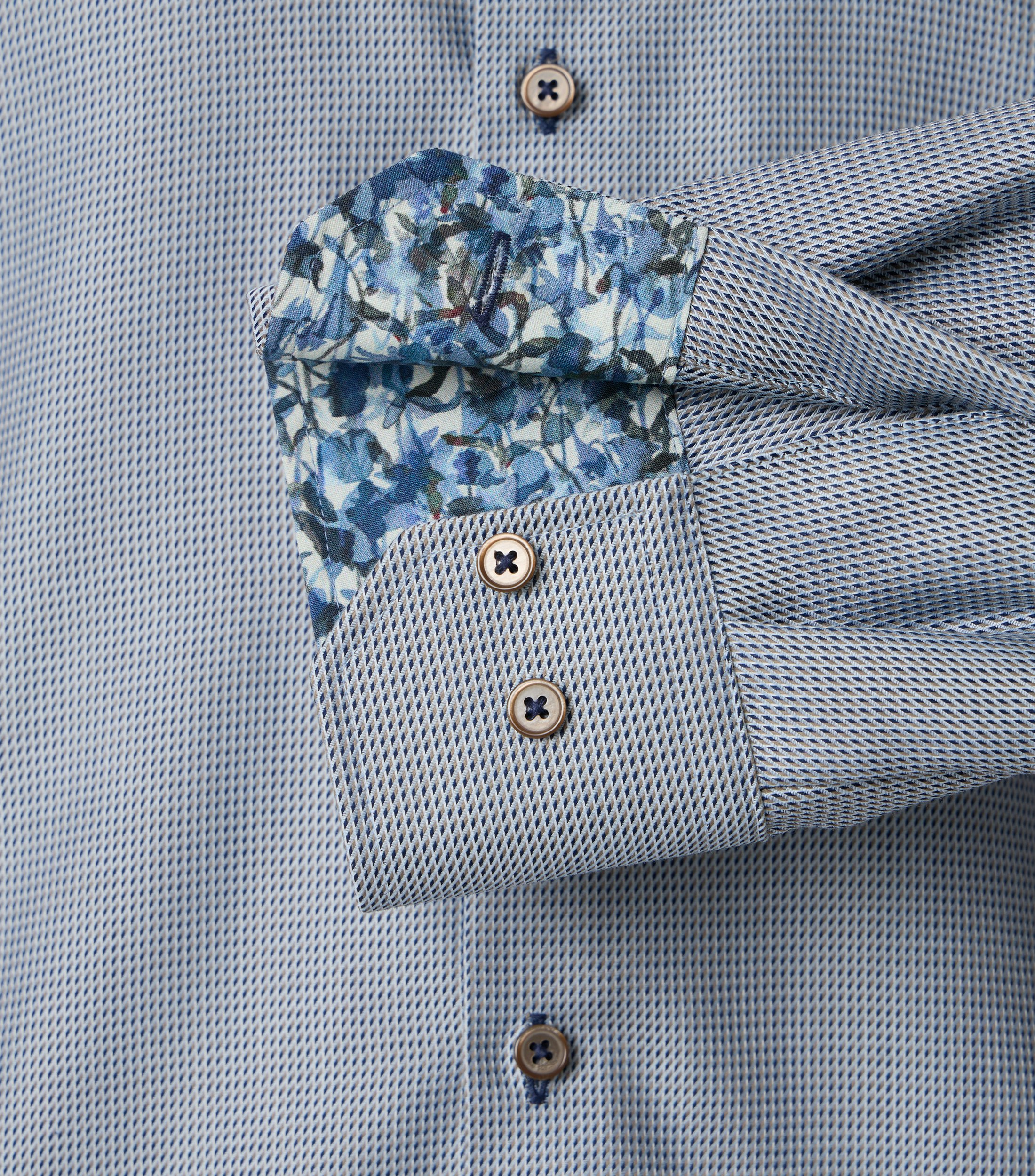 Das Model trägt ein Businesshemd im uni Muster in der Farbe Hellblau