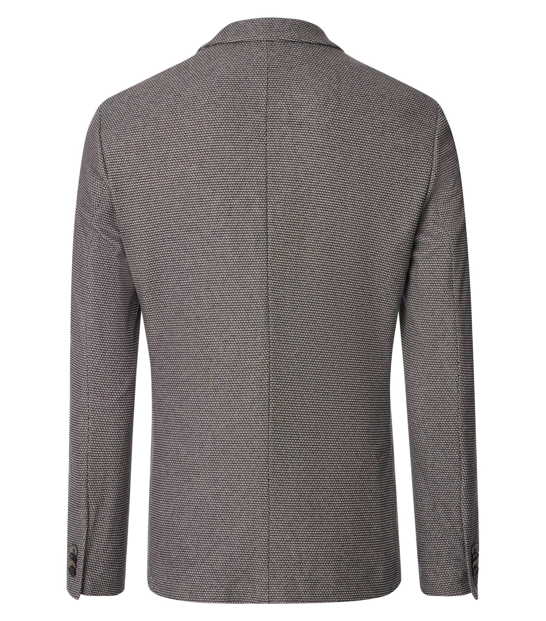 Das Model trägt ein Sakko im uni Muster in der Farbe Beige