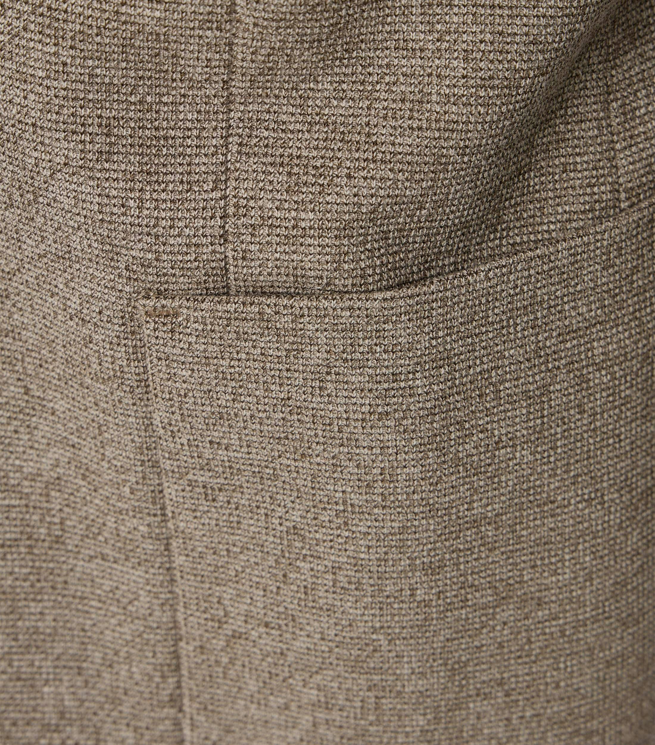 Das Model trägt ein Sakko im uni Muster in der Farbe Beige