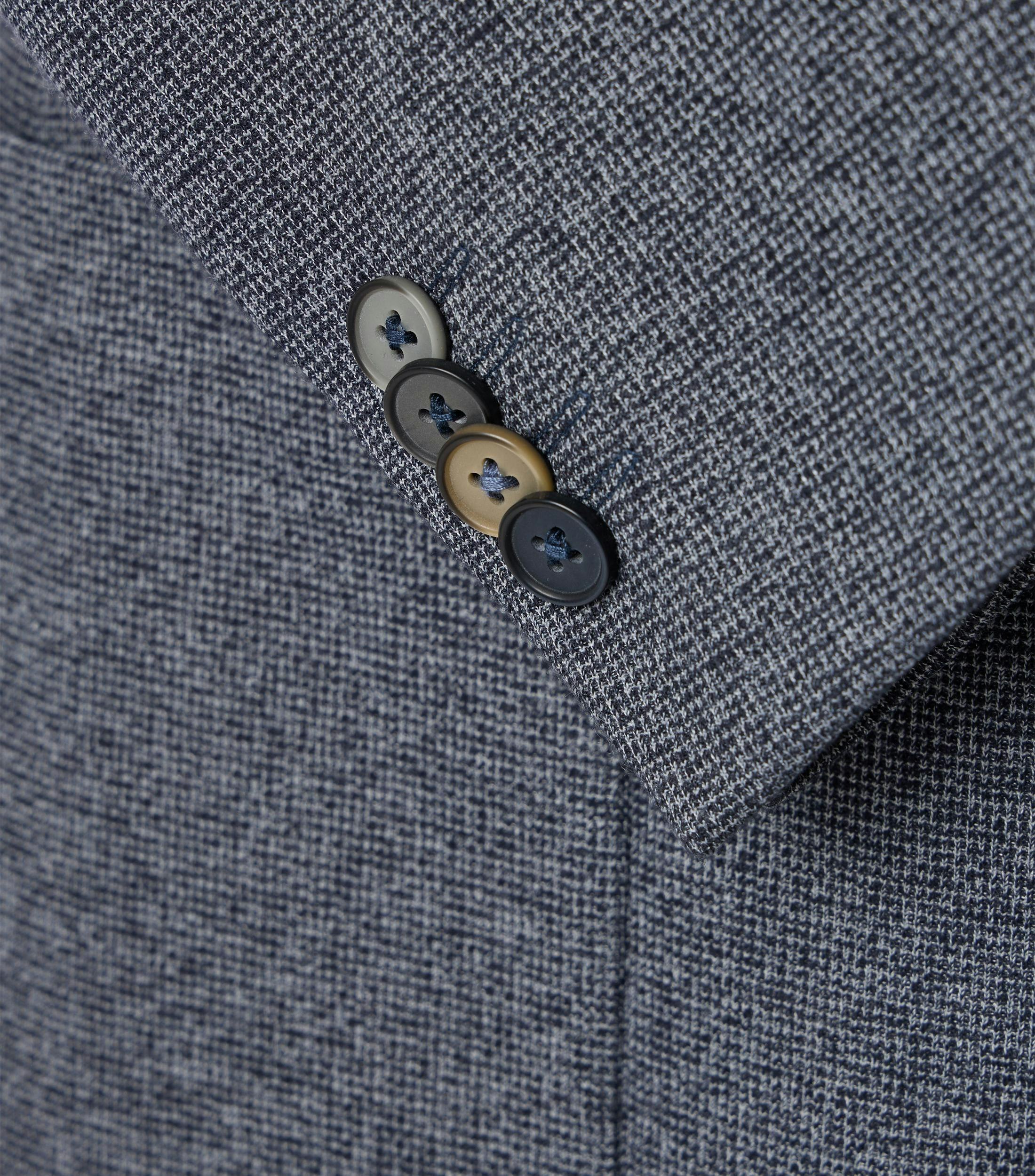 Das Model trägt ein Sakko im uni Muster in der Farbe Grau