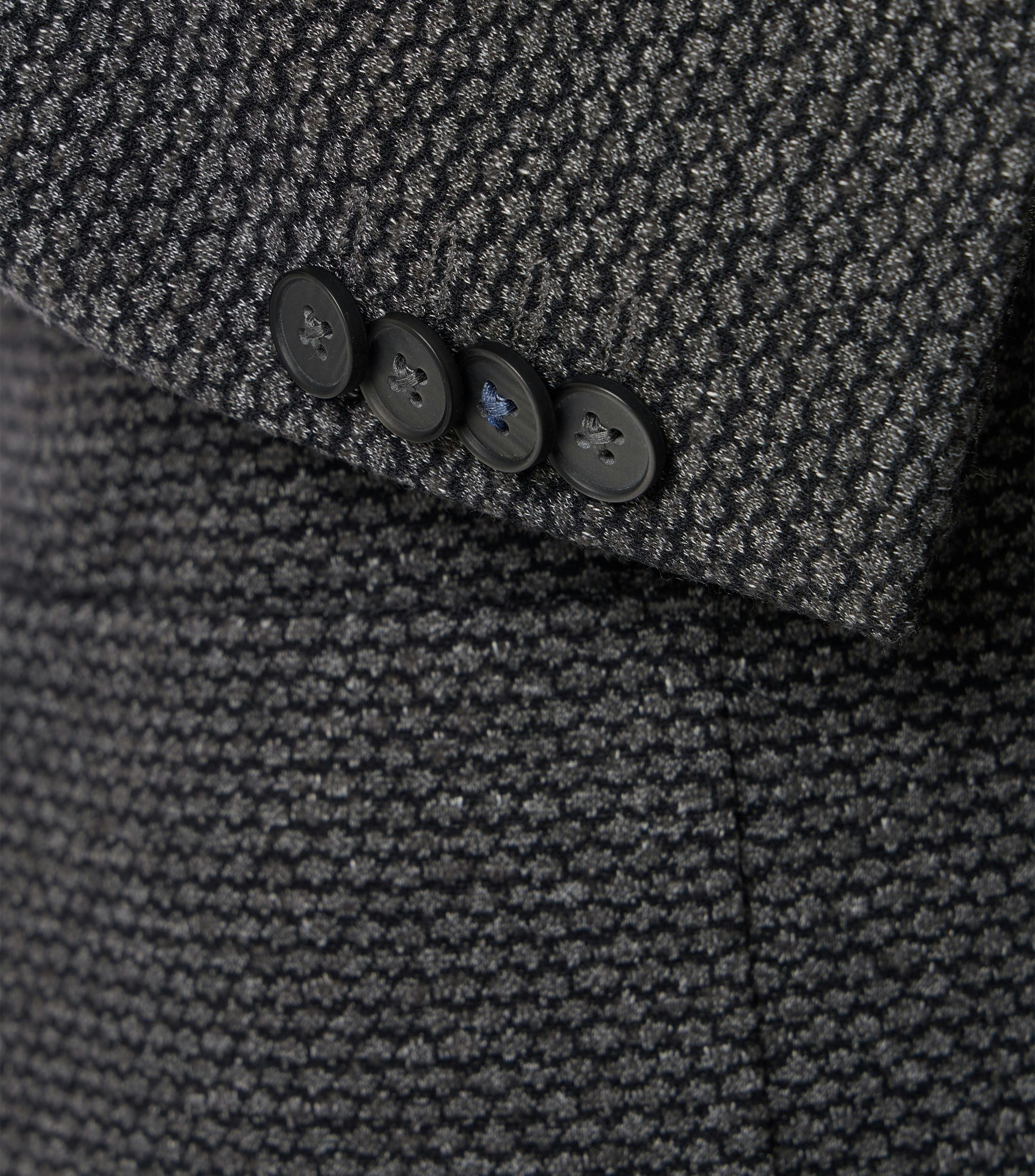 Das Model trägt ein Sakko im uni Muster in der Farbe Dunkelgrau