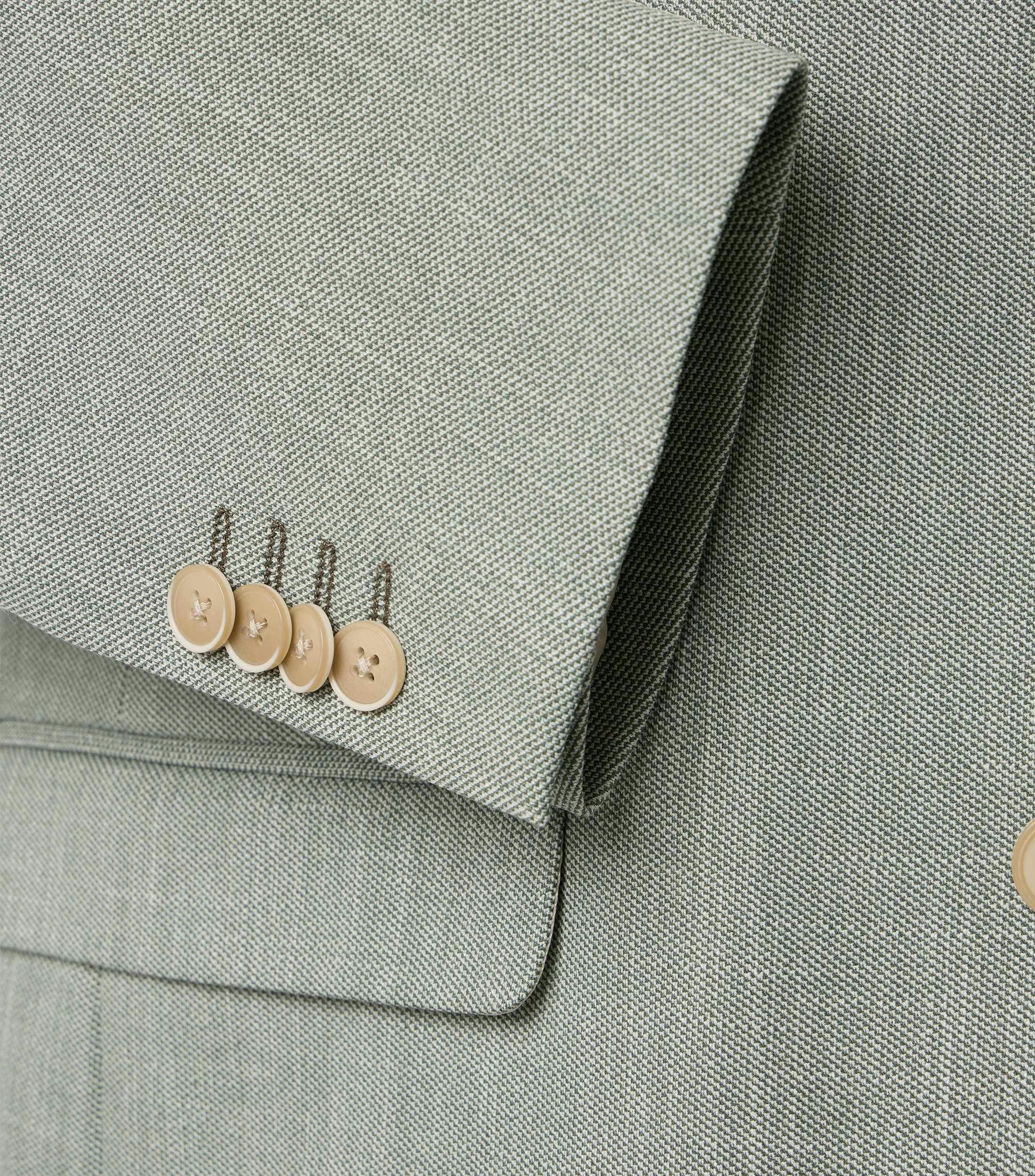 Das Model trägt ein Sakko im uni Muster in der Farbe Grün