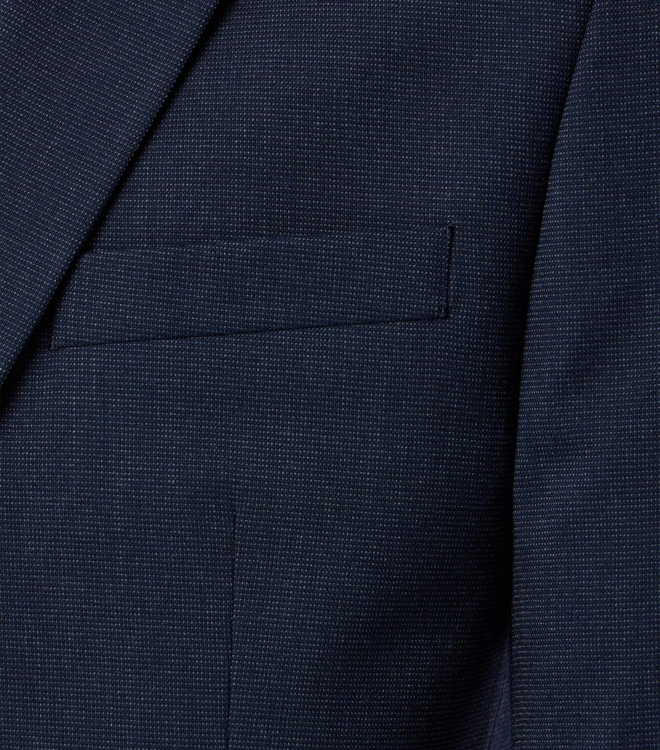 Das Model trägt ein Sakko im uni Muster in der Farbe Dunkelblau