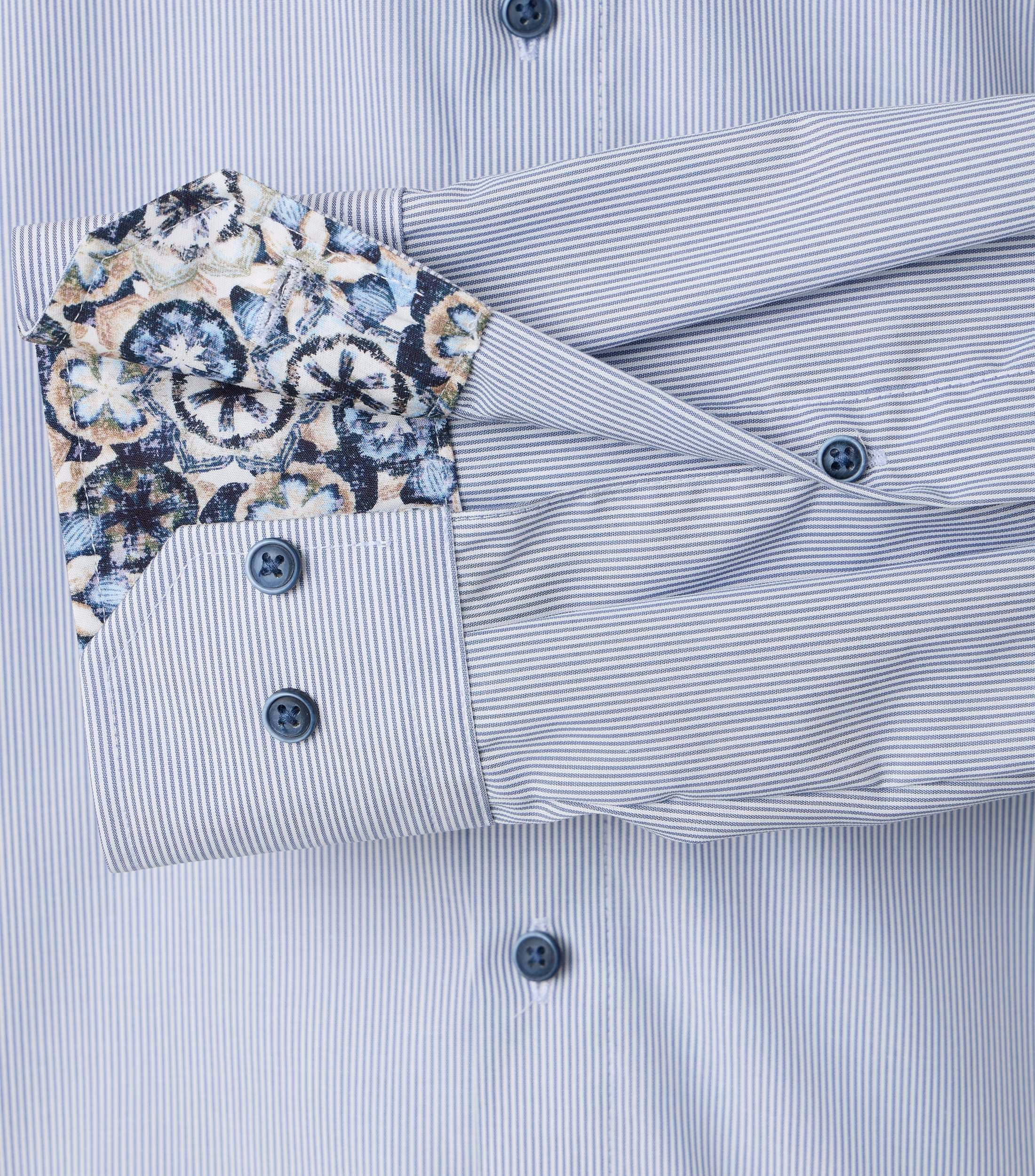 Das Model trägt ein Businesshemd im gestreift Muster in der Farbe Hellblau