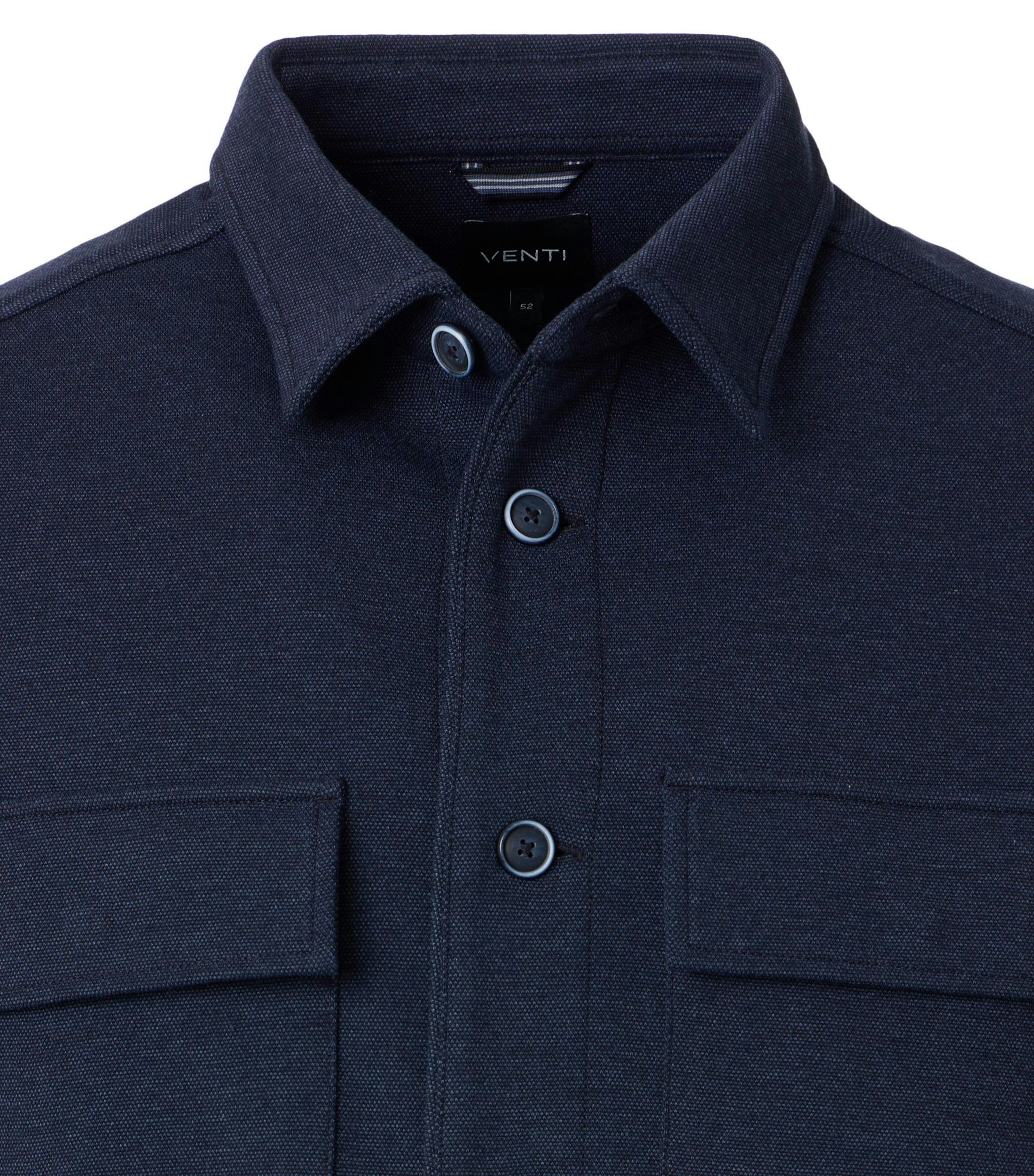 Das Model trägt ein Businesshemd im uni Muster in der Farbe Blau